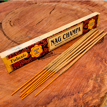 Caixa de incenso nag champa e alguns incensos fora da caixa para decoração em cima de uma mesa.