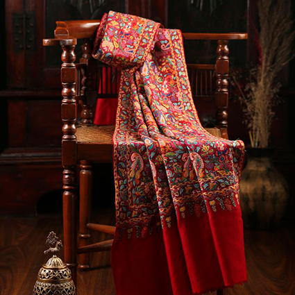 Pashmina vermelha com estampa diversificada exposta em uma cadeira.